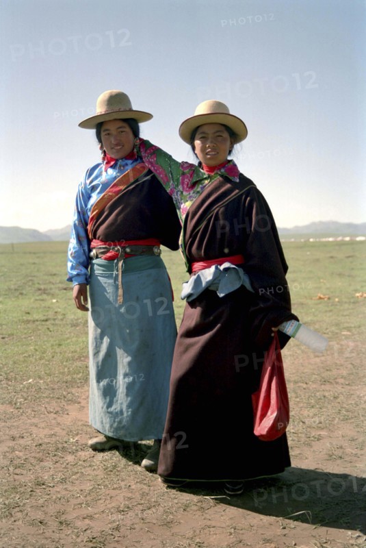 CHINA, Gansu, Xiahe, Full length portrait of two sisters travelling on foot to local festival