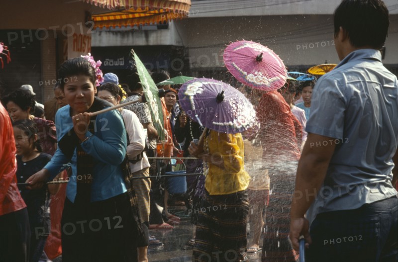 THAILAND, North, Chiang Mai , Girls with umbrellas being sprayed with water on the street during water festival.