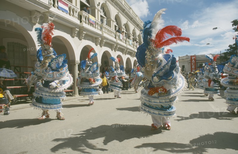 BOLIVIA, Oruro, Carnival masqueraders in colourful animal costumes in a street lined with colonial buildings