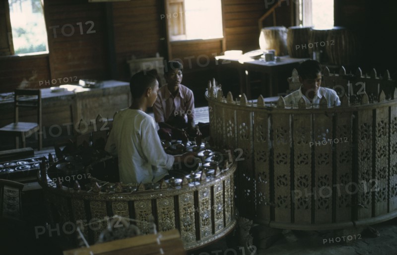 MYANMAR, Mandalay, Musicians playing classical musical instruments comprising of drums and percussion instruments in an elaborately carved circle. Pat Waing