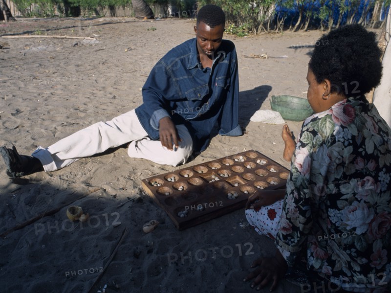 TANZANIA, Pangani, Fishing village with a couple playing an age old game called Mbao