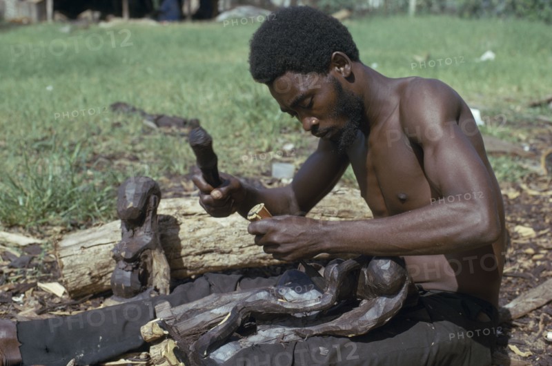 TANZANIA, Craft, Makonde man carving traditional wooden sculpture.