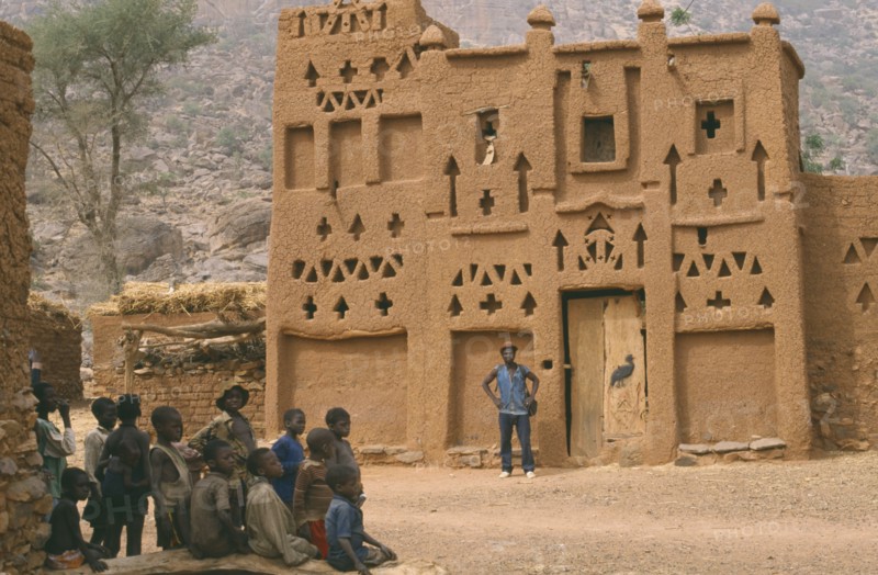 MALI, Architecture, Dogon village Elders house with man standing outside and group of children in the foreground.