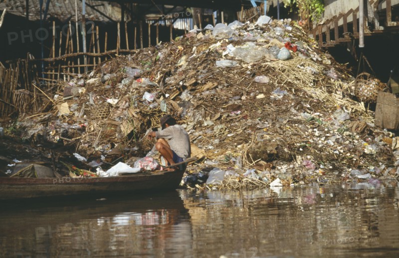 VIETNAM, Ho Chi Minh City, Garbage on the Rach Thi Nghe a filthy backwater of the Saigon River with passing boy on boat