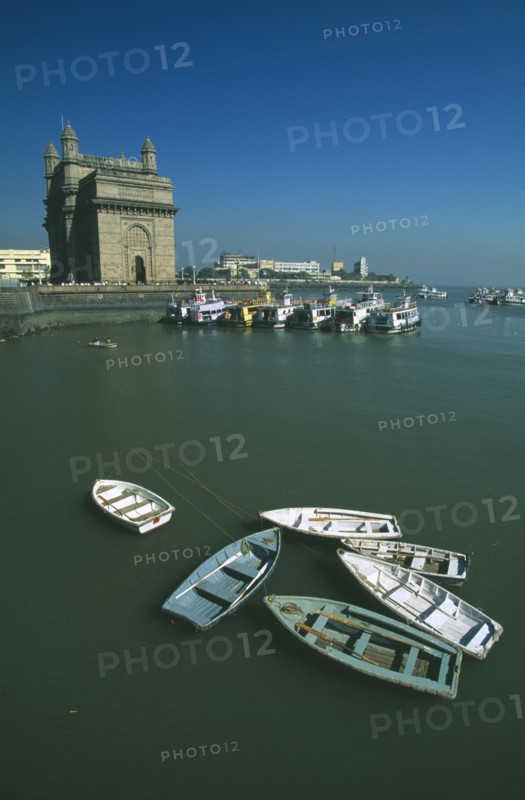 INDIA, Maharashtra, Bombay, Colaba area.  View over harbour toward the Gateway of India with ferries to Elephants Island and wooden rowing boats in the foreground.
