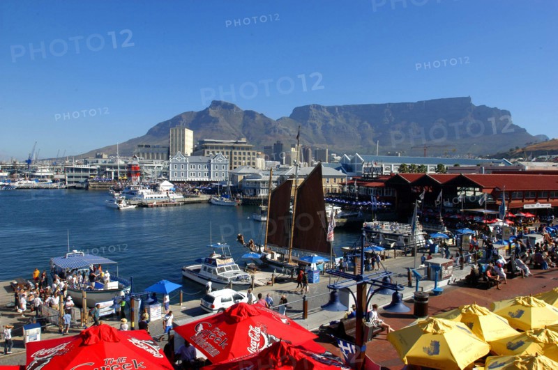 SOUTH AFRICA, Western Cape, Cape Town, View over the waterfront area with brightly coloured umbrellas in the foreground and Table Mountain in the background