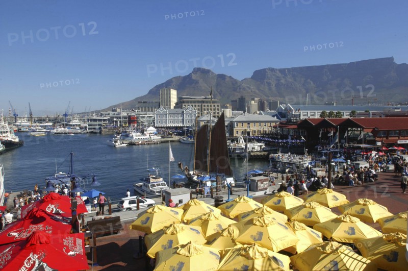 SOUTH AFRICA, Western Cape, Cape Town, View over the waterfront area with brightly coloured umbrellas in the foreground and Table Mountain in the background