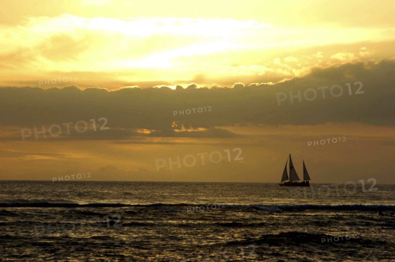 USA, Hawaii, Honolulu, Sunset over the sea with passing sail boat