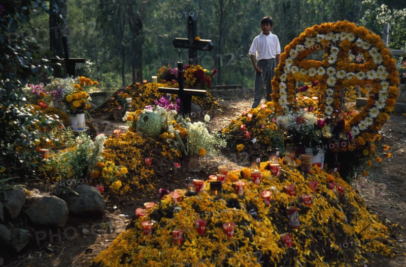 MEXICO, Michoacan State, Patzcuaro, Graves in Tzurumutaro Cemetary decorated with flowers fruit and candles for Day of the Dead celebrations.