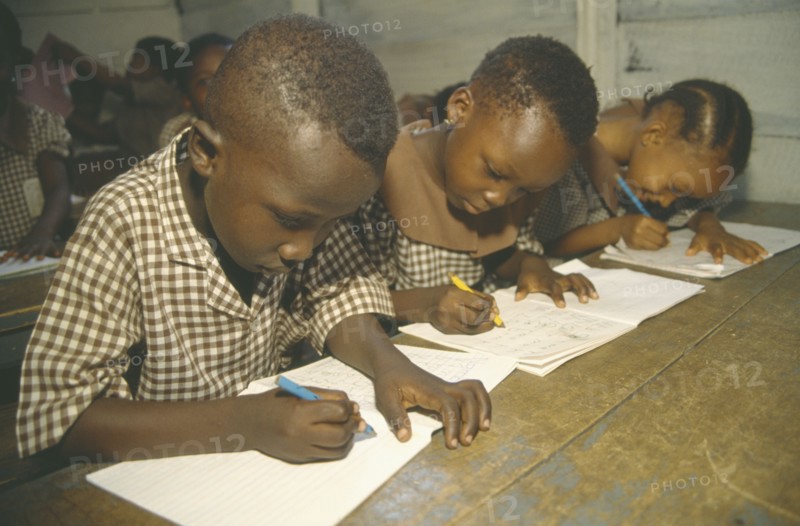 GHANA, Accra, Primary school pupils writing at their desks.
