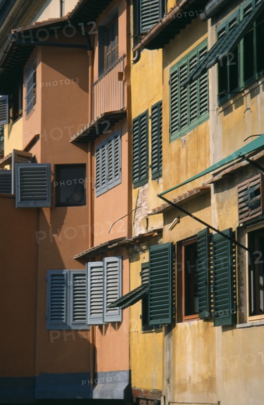 ITALY, Tuscany, Florence, Ponte Vecchio. Facades of colourful buildings with detail of wooden shutters seen in golden light