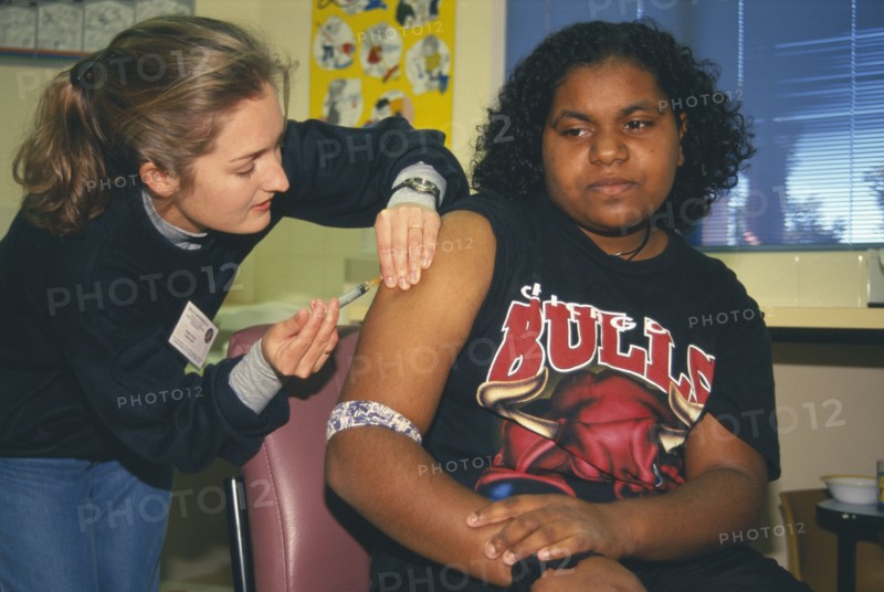 AUSTRALIA, Western Australia, Kalgoorlie, Aboriginal girl receiving Rubella vaccination from female nurse.
