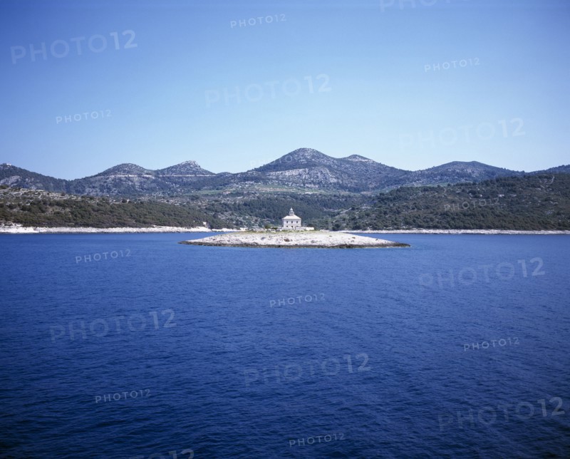 CROATIA, Dalmatia, View over water toward small islet between Sibenik and Trogir with lighthouse in the centre