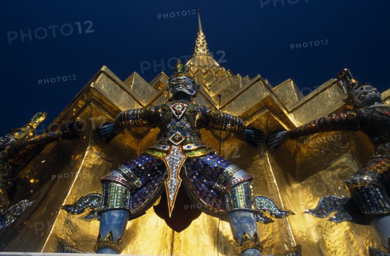THAILAND, Bangkok, Grand Palace. Demon statue at the base of a spire or prang.