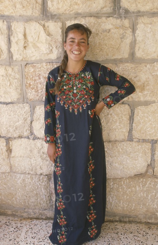WEST BANK, People, Young woman in traditional Palestinian embroidered dress in National colours