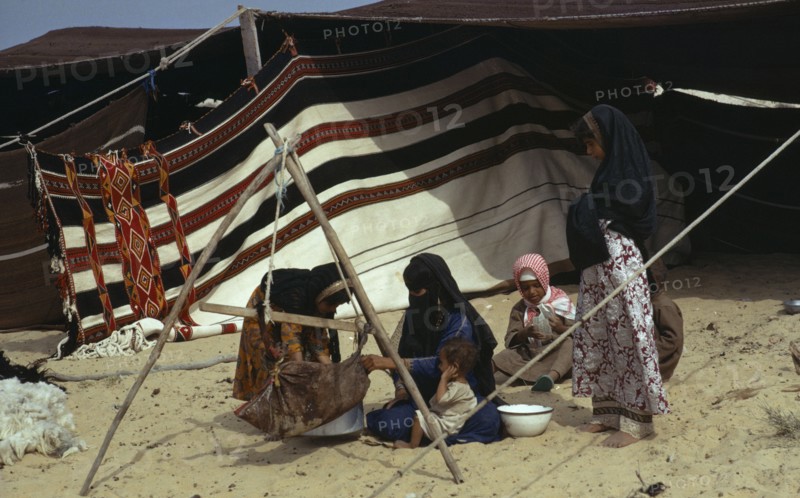 QATAR, People, Bedouin women and children sitting on sand outside tent