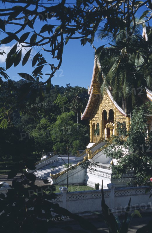 LAOS, Luang Prabang, Royal Palace.  Exterior of temple part framed by tree branches.