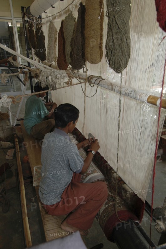 INDIA, Rajasthan, Jaipur, Boys weaving a Rajastan carpet on a large loom