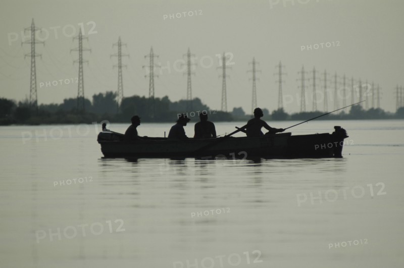 ROMANIA, Tulcea, Danube Delta Biosphere Reserve, Silhouette of a two canoes with sports fishers on the Sulina arm of the Danube river