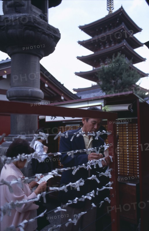 JAPAN, Honshu, Tokyo, Asakusa. People tying Omikuji or Fortune papers at Senso Ji Temple