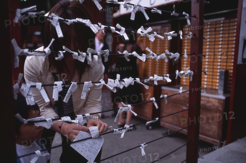 JAPAN, Honshu, Tokyo, Asakusa. People tying Omikuji or Fortune papers at Senso Ji Temple