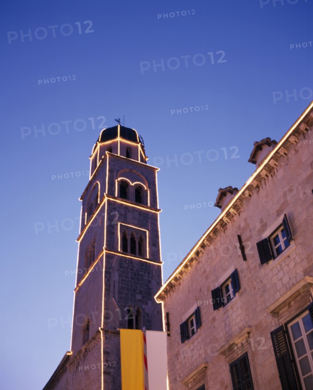 CROATIA, Dalmatia, Dubrovnik, Angled view looking up at the Francisan Monastery tower illuminated at dusk