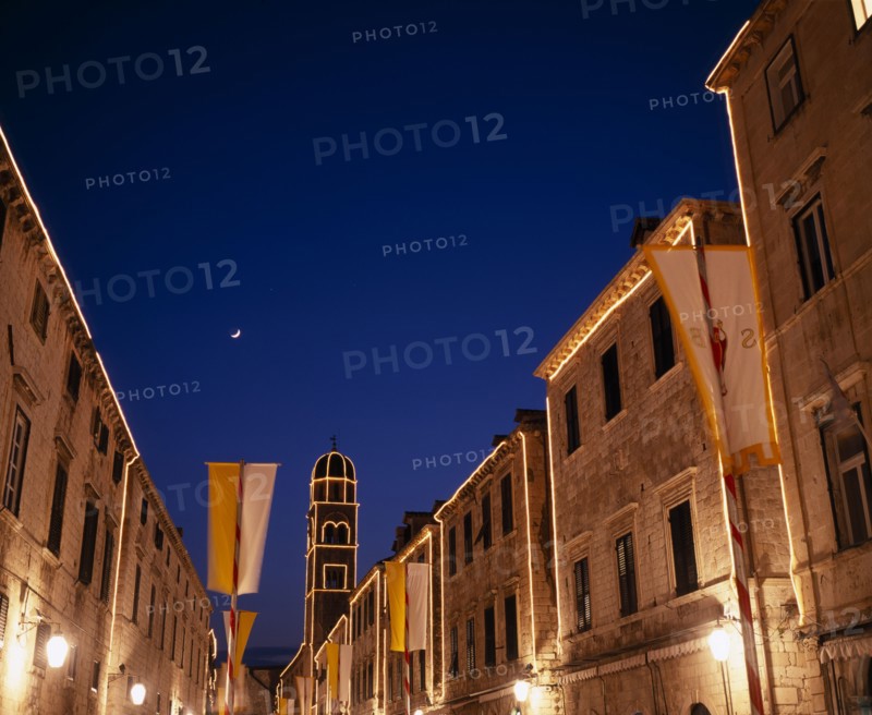 CROATIA, Dalmatia, Dubrovnik, View along the Stradun toward the Franciscan Monastery illuminated at dusk
