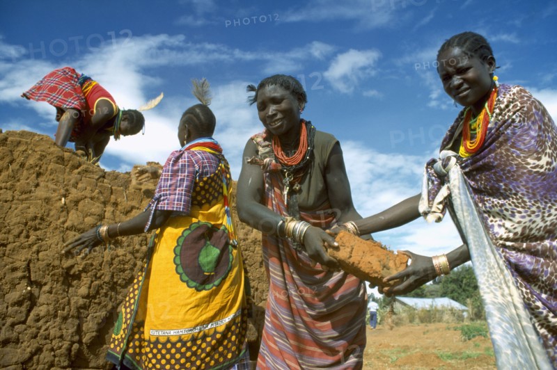 UGANDA, Industry, Construction, Brightly dressed Karamojong women making bricks. Blue sky behind.