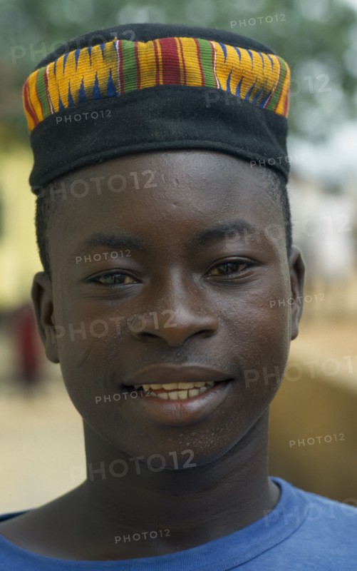 GHANA, Tribal People, Portrait of boy wearing hat made from traditional kente cloth.