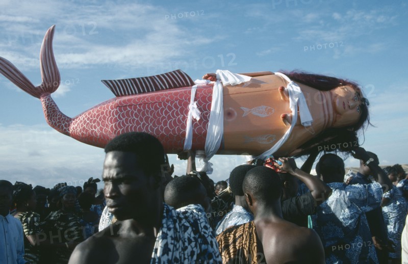GHANA, Teshie, Coffin made and painted to resemble a mermaid for Ga tribal priestess of sea god carried by funeral guests.