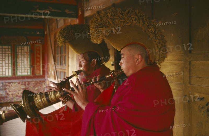 CHINA, Qinghai, Queshang Lamasery, Yellow hat Buddhist Monks playing horn instruments in the temple