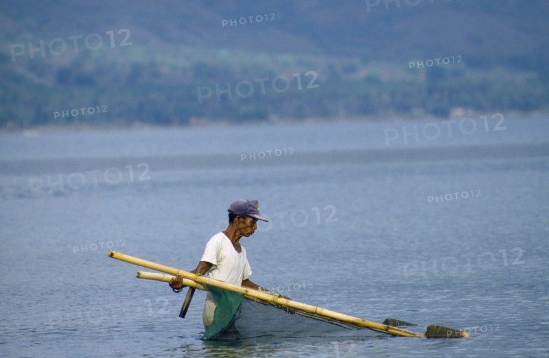 INDONESIA, Palu, Man fishing near beach with hand net