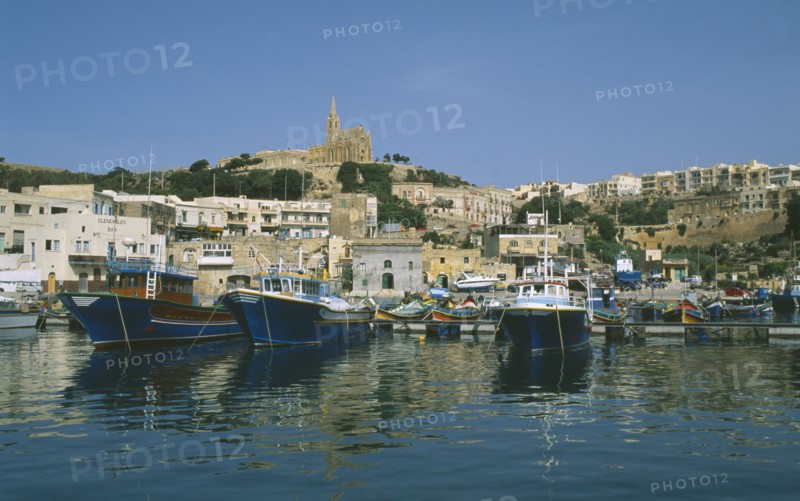 MALTA, Gozo, Mgarr, Fishing boats in harbour overlooked by cathedral.