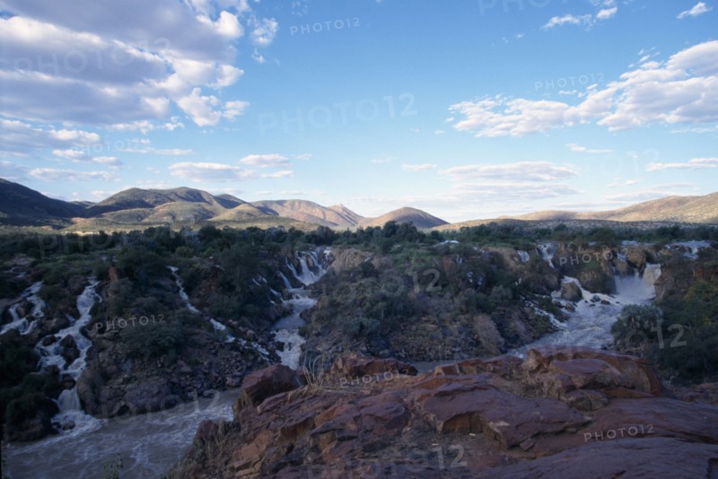 NAMIBIA, Epupa Falls, Water gushing through rocky cliffs into fast flowing river.
