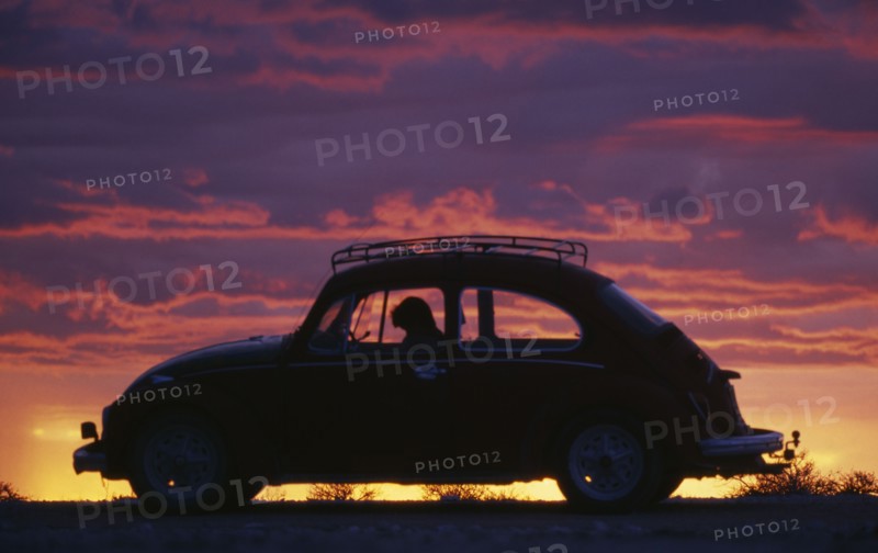 NAMIBIA, Transport, VW Beetle in silhouette against dramatic sunset sky.
