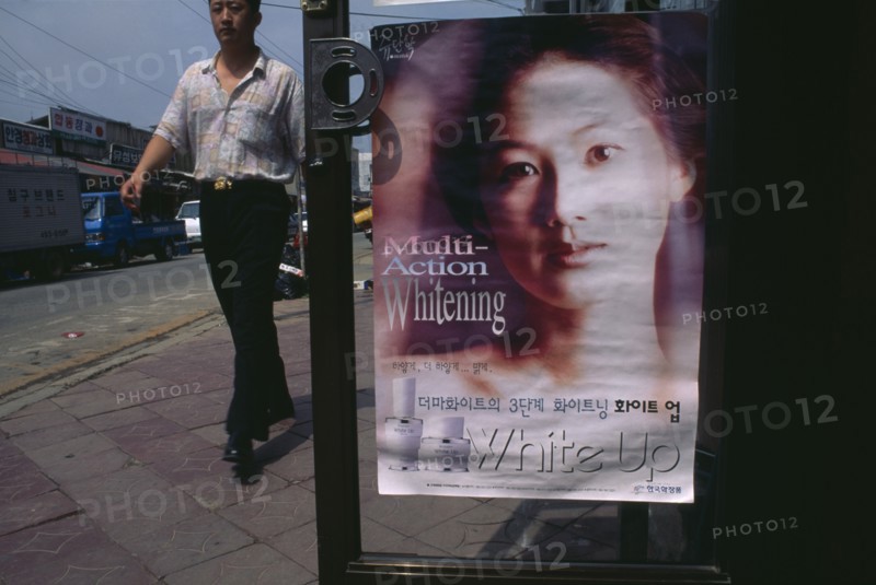 SOUTH KOREA, Sokcho, Man walking past advertisment for skin whitening cream