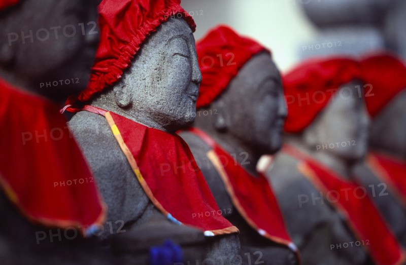 JAPAN, Honshu, Kamakura, View along row of Jizo statues dressed in red bibs by bereaved mothers and other sufferers