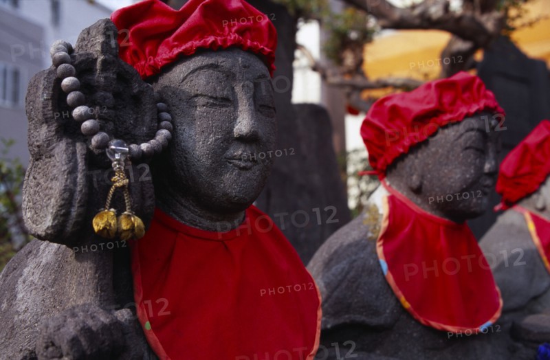 JAPAN, Honshu, Kamakura, Row of Jizo statues dressed in red bibs by bereaved mothers and other sufferers
