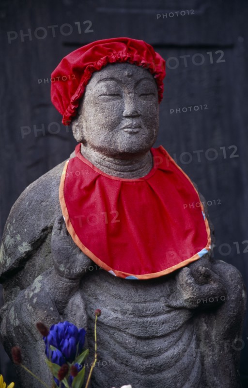 JAPAN, Honshu, Kamakura, Jizo statue traditionally dressed in red bibs by bereaved mothers and other sufferers