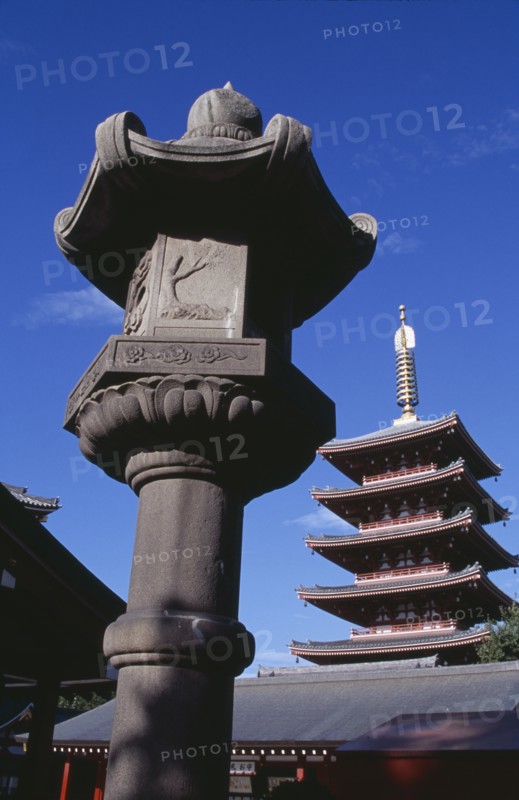 JAPAN, Honshu, Tokyo, Asakusa. Senso Ji Temple. Angled view of the Five Storey Pagoda with ornamental stone column in the foreground