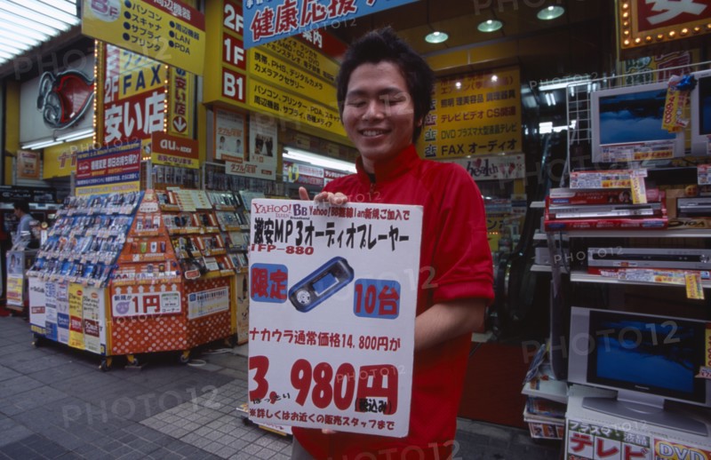 JAPAN, Honshu, Tokyo, Akihabara Electronics District. Vendor holding poster outside his electrical store