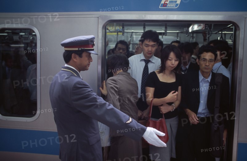 JAPAN, Honshu, Tokyo, Passengers on crowded train at Ueno Station with train guard standing on the platform