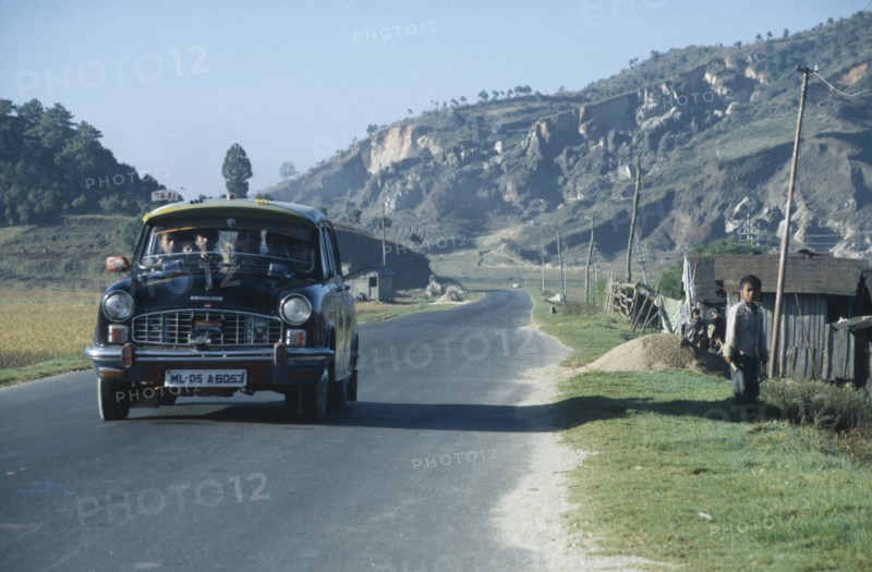 INDIA, Meghalaya, Packed ambassador taxi on road through rural area in north east India.