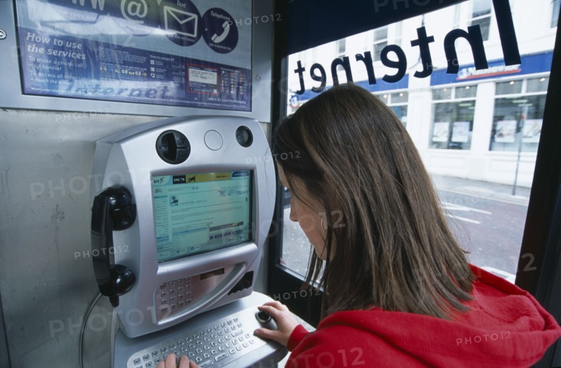 COMMUNICATIONS, Phone Box, Young woman using a public BT Internet phone booth.