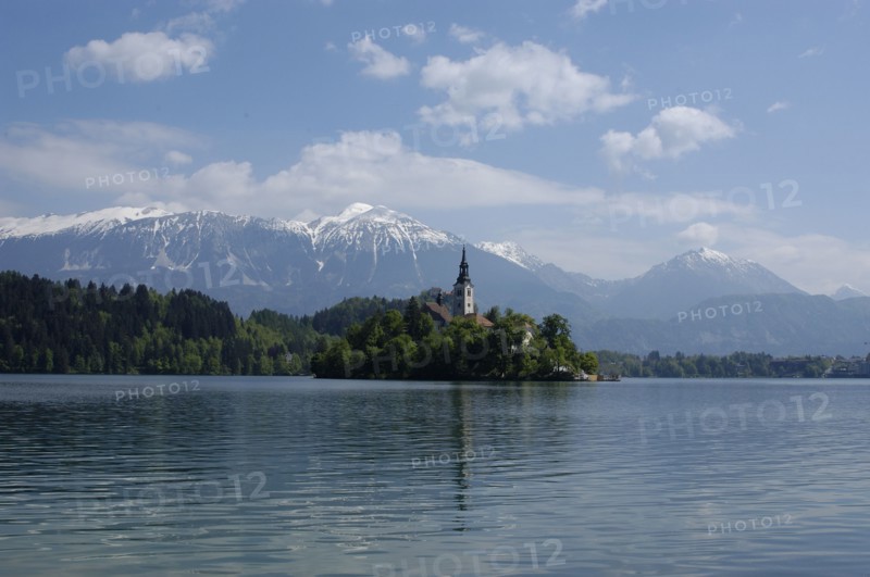 SLOVENIA, Lake Bled, View over the lake toward Bled Island and tower of the Church of the Assumption with snow capped peaks of the Julian Alps behind