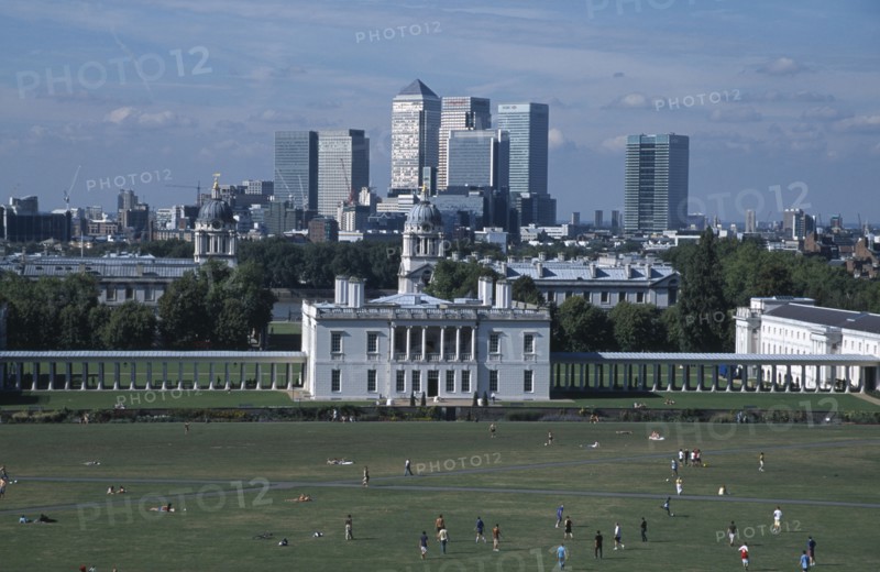 ENGLAND, London, Greenwich. View over lawn toward Queens House with the Canary Wharf skyline beyond