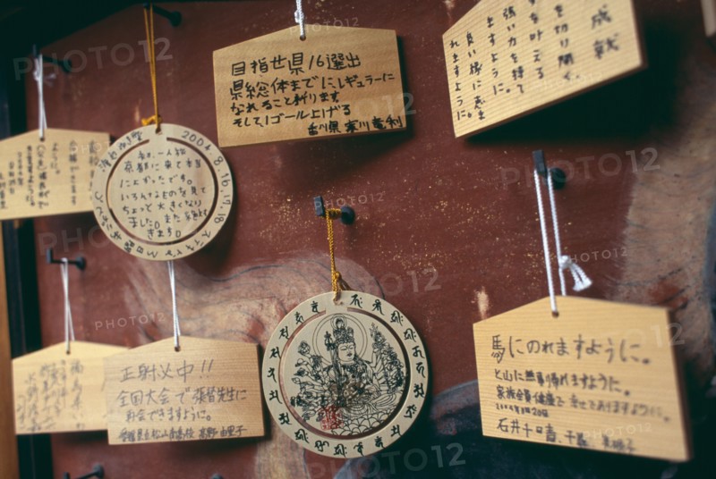 JAPAN, Honshu, Kyoto, Sanjusangen do Temple. Ema wooden votive tablets hanging from hooks on a wall