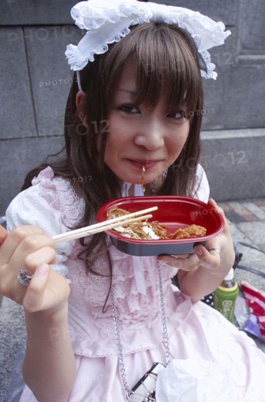 JAPAN, Honshu, Tokyo, Harajuku District. Portrait of young teenage girl eating noodles