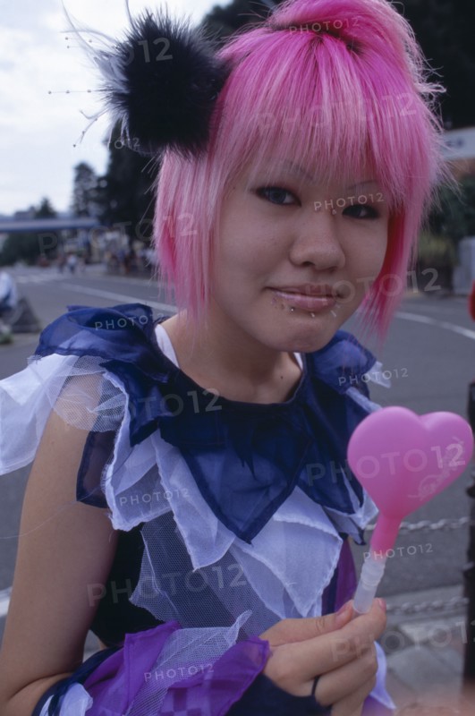 JAPAN, Honshu, Tokyo, Harajuku District. Portrait of a teenage girl with pink hair and several facial piercings
