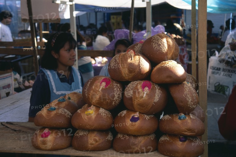 MEXICO, Oaxaca, Girls selling decorated bread for Day of the Dead.